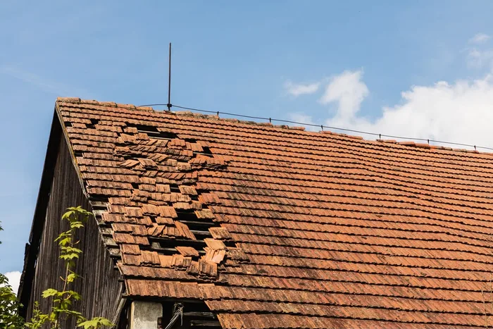 Toiture en tuiles endommagée : tuiles cassées et déplacées laissant les liteaux à nu